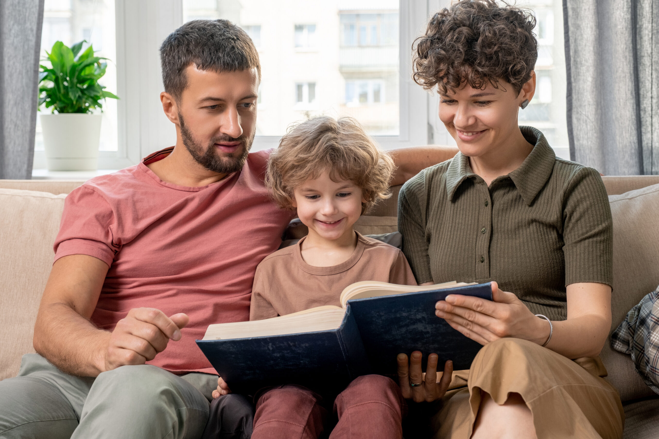Family reading a book together on a sofa