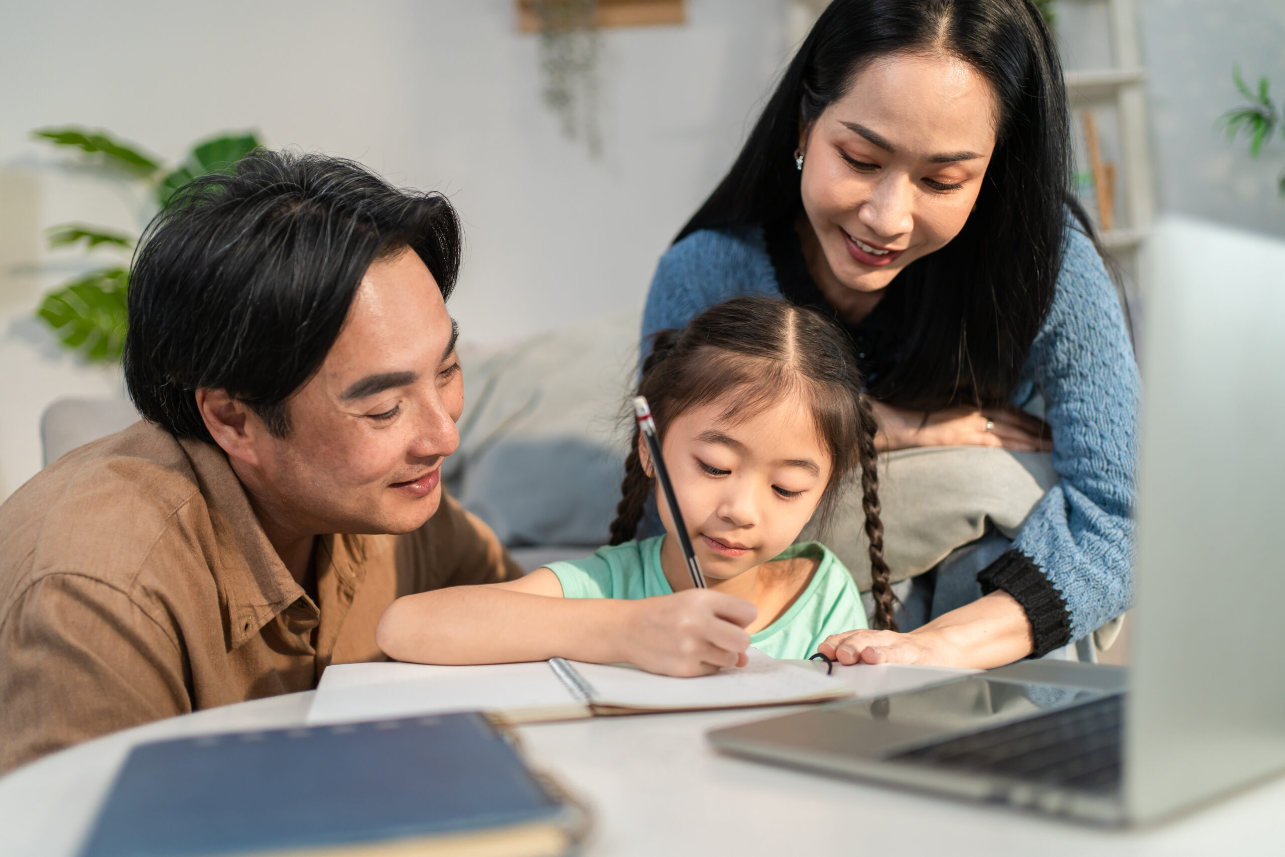 Parents helping their daughter with homework at home